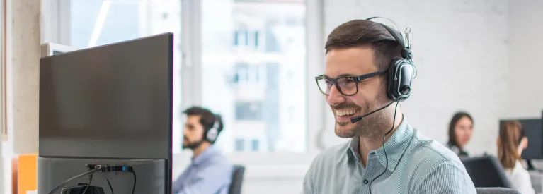 Energia+ Pomoc IT. Konsultant ze słuchawkami zdalnie pomaga klientom