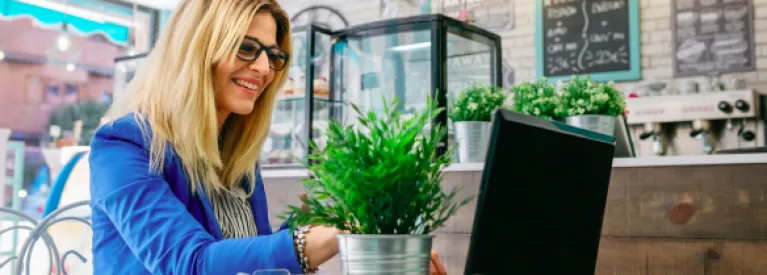 Kobieta pisząca na laptopie w kawiarni