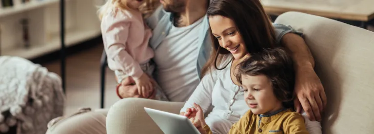 Rodzina siedzi na kanapie i sprawdzają coś na tablecie